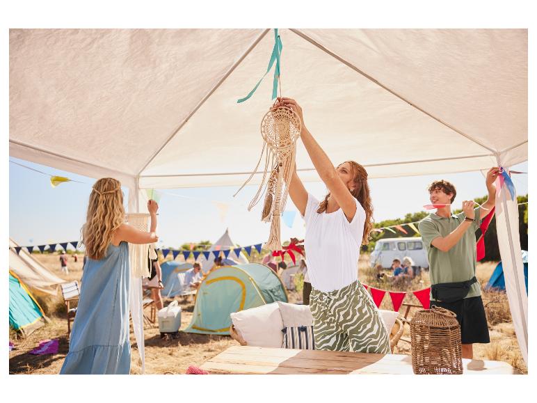 Frauen dekorieren einen Pavillon mit Traumfängern und Girlanden auf einem Boho-Festival.