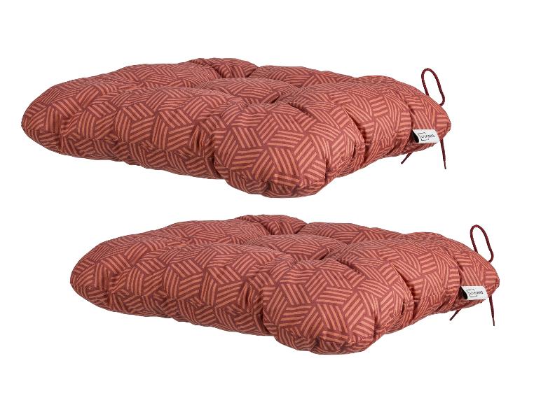 Zwei rote Sitzkissen mit geometrischem Muster und Bindebändern.