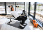 Mann trainiert mit Hanteln auf einer Hantelbank in einem hellen Fitnessstudio.