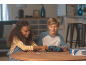 Zwei Kinder setzen ein blaues 3D-Auto-Puzzle auf einem Holztisch zusammen.