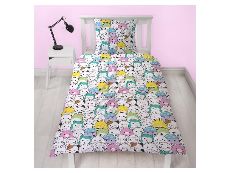 Kinderbettwäsche mit bunten Cartoon-Tieren auf einem Bett mit weißem Rahmen.