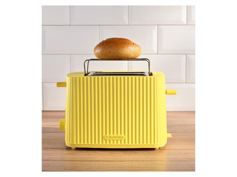 Gelber SilverCrest Toaster mit Brötchen auf dem Aufwärmrost, auf einer Holztheke.