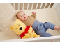 Lächelndes Baby liegt im Kinderbett mit einem Teddybär.