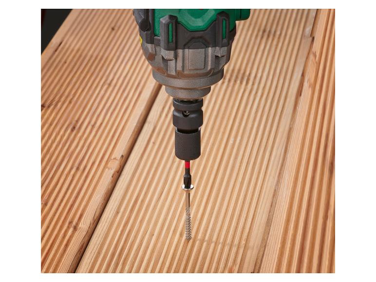 Ein grüner Schraubendreher schraubt eine Schraube in Holz.