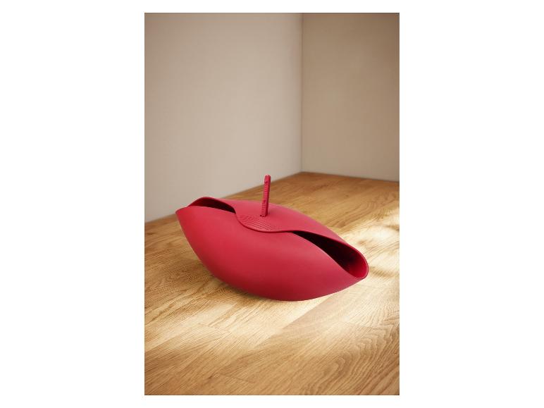 Ein roter, blütenblattartiger Brotkorb auf einer Holzoberfläche.