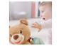 Baby greift nach einem weichen Teddybär mit Marienkäfer-Dekoration.