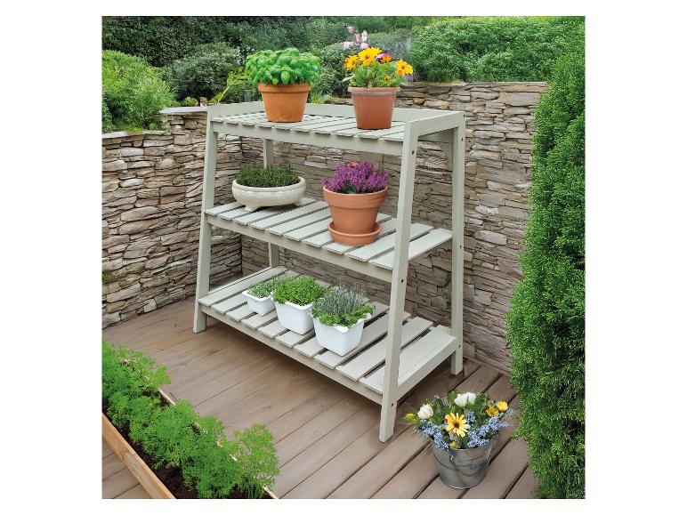 Dreistöckiges Holzregal mit verschiedenen Pflanzen und Blumen auf einer Terrasse.
