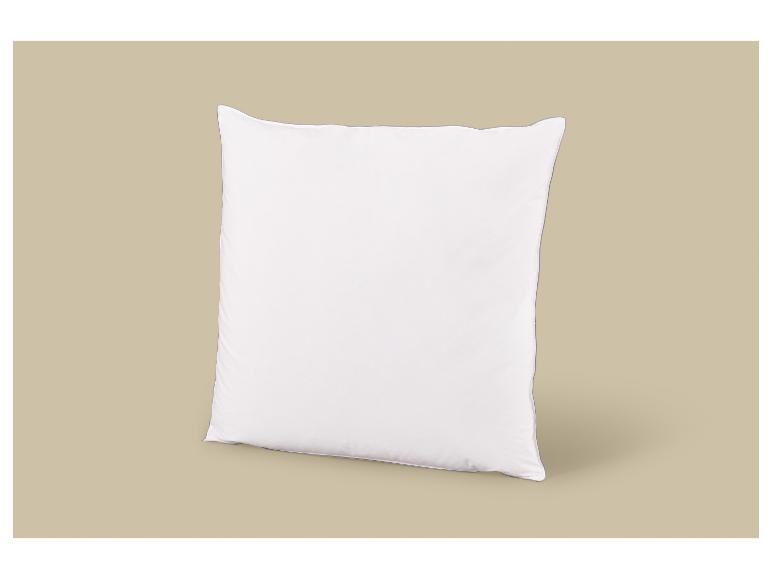 Ein weißes Kissen mit grauem Rand, aufrecht stehend auf beigem Hintergrund.