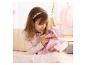 Mädchen in rosa Oberteil spielt mit Babypuppe in rosa Outfit und Schnuller.