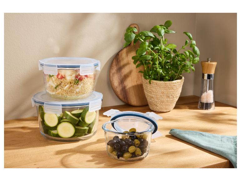 Glas-Frischhaltedosen mit frischen Zutaten auf einer Holztheke.