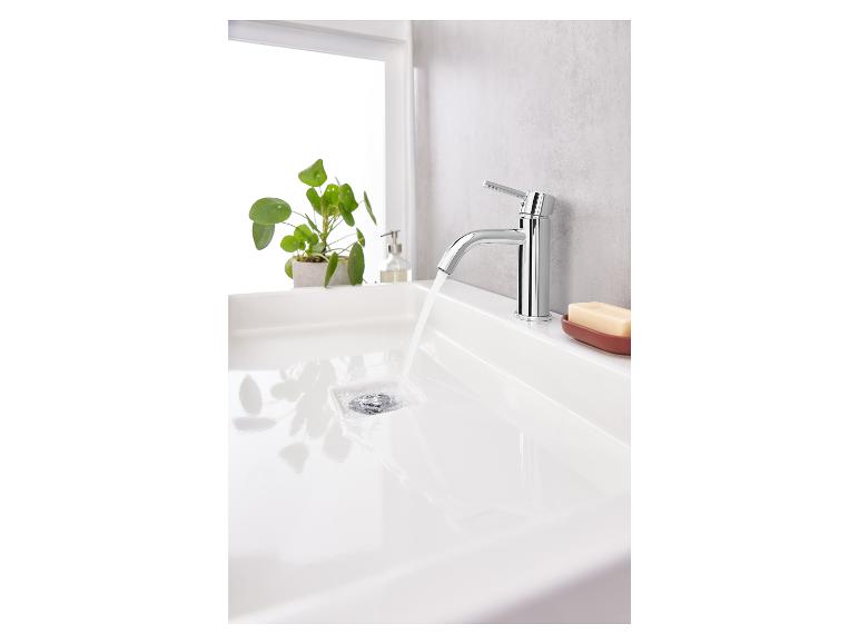 Ein Waschbecken mit einem verchromten Wasserhahn, aus dem Wasser fließt.