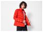 Eine Frau trägt eine rote, gesteppte Jacke.