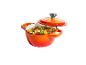 Oranger Gusseisentopf mit Deckel, gefüllt mit einem Eintopf aus Fleisch, Bohnen und Gemüse.