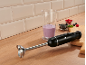 Schwarzer Stabmixer mit Beerensmoothie und Früchten auf einer Holztheke.