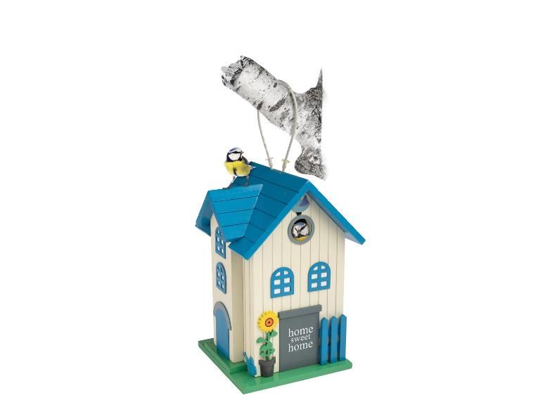 Vogelhaus mit blauem Dach, einer Sonnenblume und zwei Vögeln, einer auf dem Dach, einer drinnen.