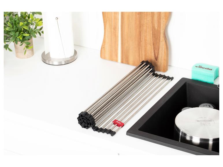 Rollbarer Abtropfständer über einer Küchenspüle mit Schneidebrett.
