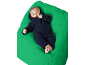 Baby in dunkelblauem Overall auf einer grünen Decke.