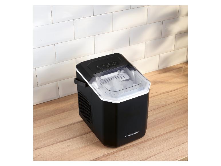 Schwarzer Eiswürfelbereiter mit transparentem Deckel, gefüllt mit Eiswürfeln, auf einer Holzarbeitsplatte.