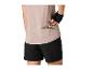 Frau in beigem Sport-T-Shirt und schwarzen Shorts nimmt einen Riegel aus der Tasche.