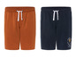 Zwei Shorts, eine in dunkelblau mit 'Summer Travel Beach Club' Print, eine in braun.