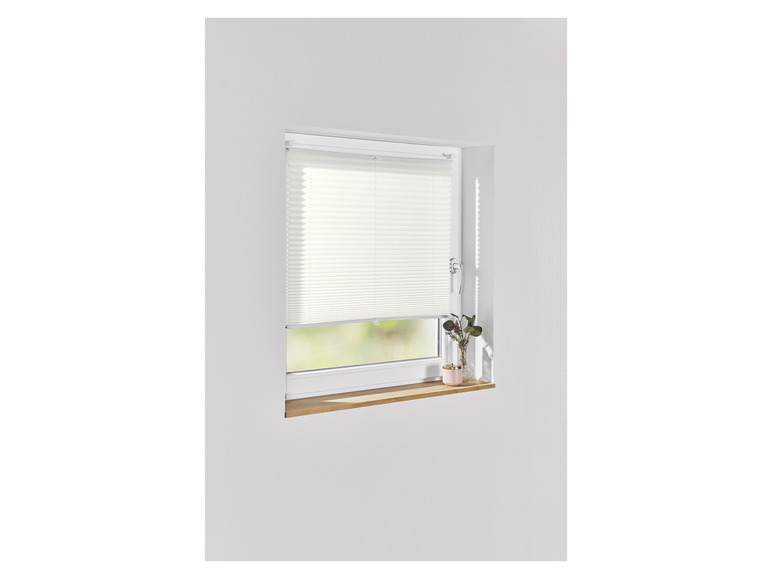 Ein weißer Plissee-Rollladen an einem Fenster.