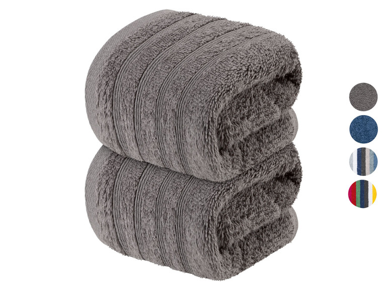 Zwei gerollte Handtücher in Grau.