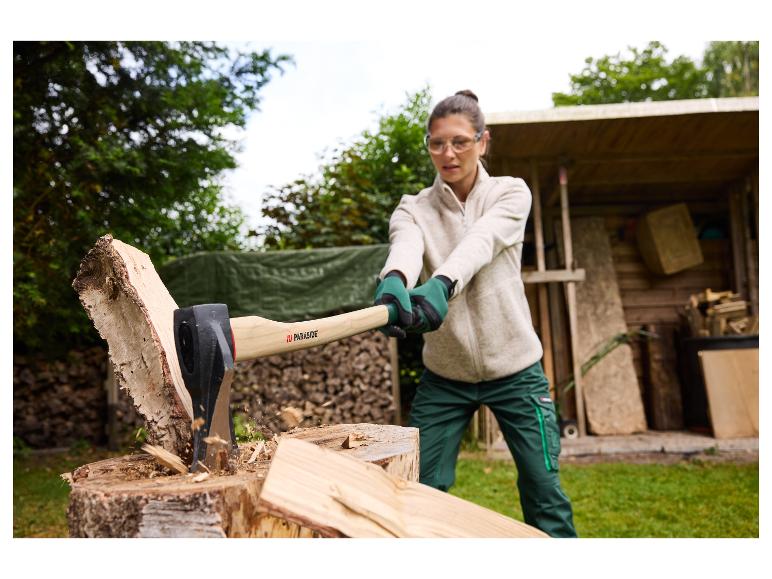 Eine Frau spaltet Holz mit einer PARKSIDE Spaltaxt im Garten.