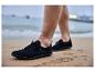 Schwarze Herrenschuhe im Sand, mit Meer im Hintergrund.