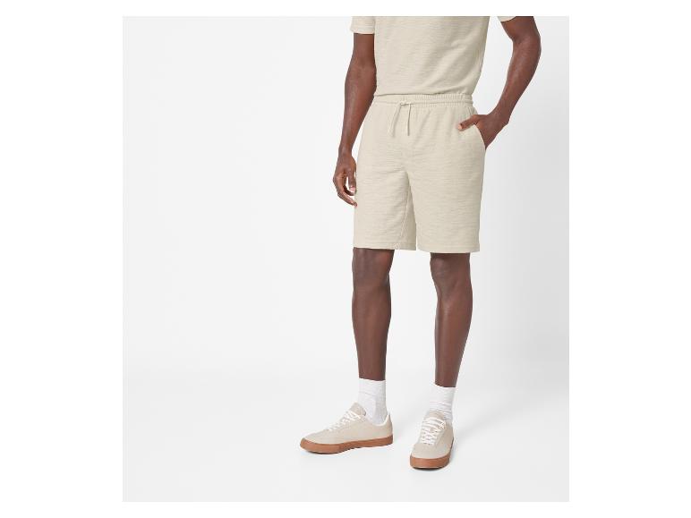 Mann in beige Shorts und Sneakers.