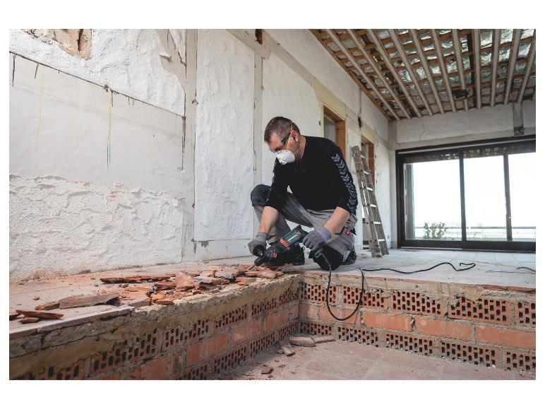 Mann entfernt Bodenfliesen mit einem Metabo Bohrhammer während der Renovierung