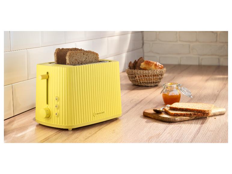 Gelber SilverCrest Toaster mit Toast, Marmelade und Brotkorb in der Küche.