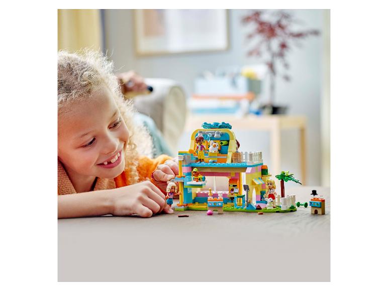 Ein lächelndes Mädchen spielt mit einem LEGO Friends Haustierrettungszentrum.