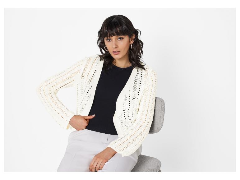 Model trägt cremefarbenen, durchbrochenen Cardigan und beige Hose.