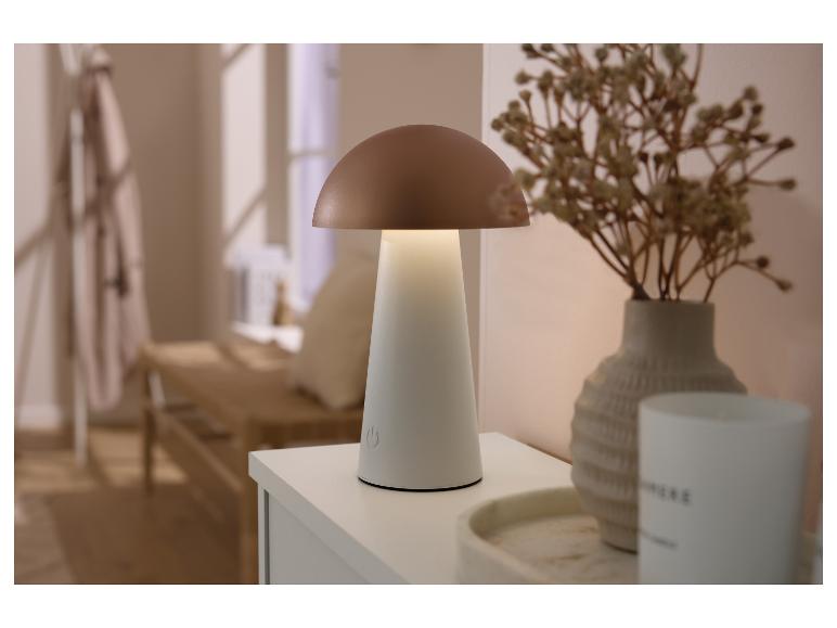 Pilzförmige Tischlampe mit kupferfarbenem Schirm und weißem Fuß, neben einer Vase mit Trockenblumen.