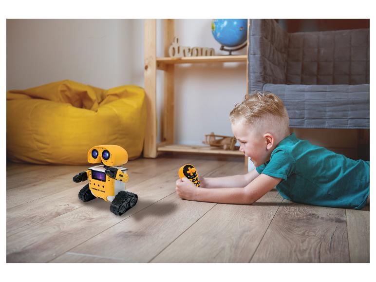 Junge spielt mit gelbem ferngesteuertem Roboter auf dem Boden.