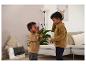 Zwei Jungen in braunen Sweatshirts spielen mit einem Walkie-Talkie im Wohnzimmer.