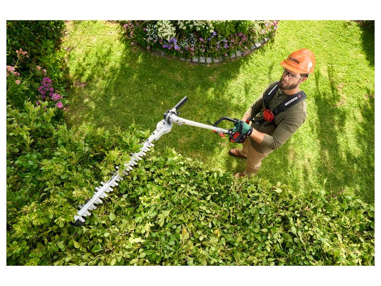Ein Mann benutzt eine elektrische Parkside Heckenschere zum Hecken schneiden.