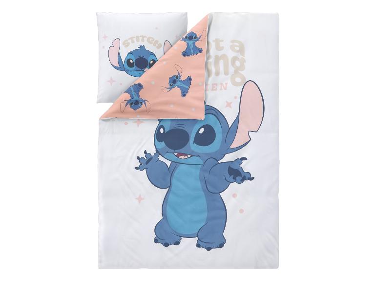 Weiße Bettwäsche und Kissen mit blauem Cartoon-Charakterdruck und Text.