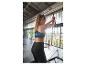 Frau in schwarzen Leggings und Sport-BH, trainiert an einem Fitnessgerät.
