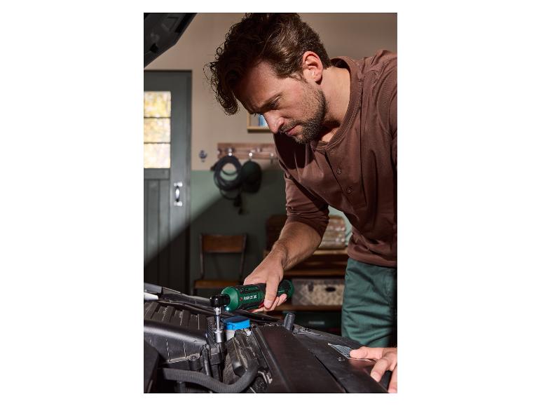 Mann benutzt einen Parkside Akku-Ratschenschrauber zur Reparatur eines Automotors.