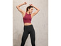 Eine Frau trägt schwarze Leggings und ein rotes Sport-Top.