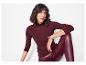 Frau in burgunderfarbenem gerippten Pullover und Kunstlederleggings.
