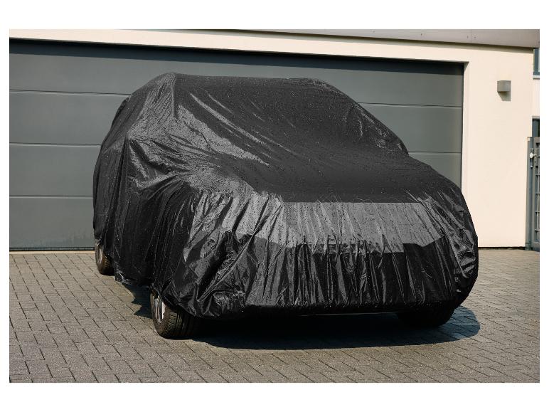 Schwarze Autoabdeckung mit Wassertropfen vor einer Garage.