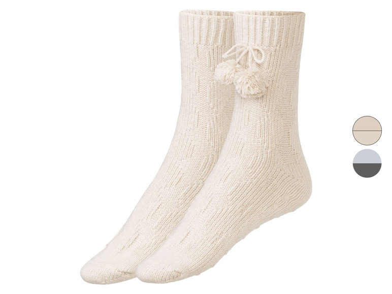 Zwei Paar gestrickte Socken mit Bommel-Verzierung.