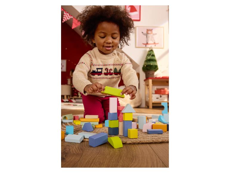 Ein Kind spielt mit bunten Bauklötzen auf einem Holzboden.