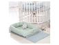 Weißes Holzbettchen mit Rollen und ein mintgrünes Babynest mit Bärenspielzeug.
