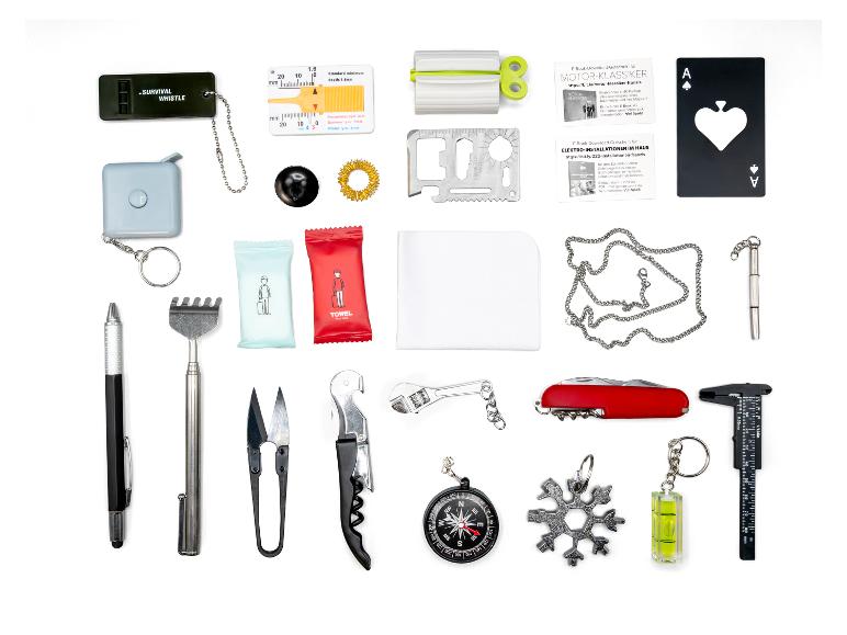 Eine Auswahl kleiner Werkzeuge und Gadgets, darunter eine Überlebenspfeife, Maßband und ein Schweizer Taschenmesser.