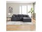 Graues Modulsofa mit Ottomane, Teppich, Beistelltisch und Pflanze in einem hellen Wohnzimmer.