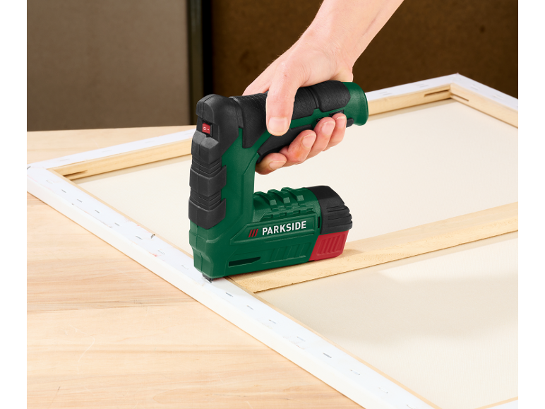 Hand benutzt einen Parkside Elektrotacker, um Leinwand auf einen Holzrahmen zu spannen.