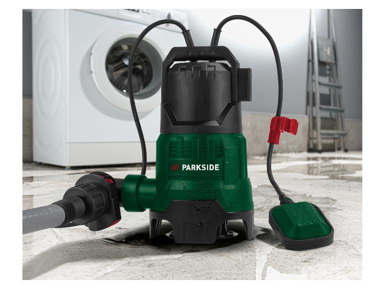 Eine Tauchpumpe mit Schlauch und Schwimmerschalter auf nassem Boden, mit einer Waschmaschine im Hintergrund.